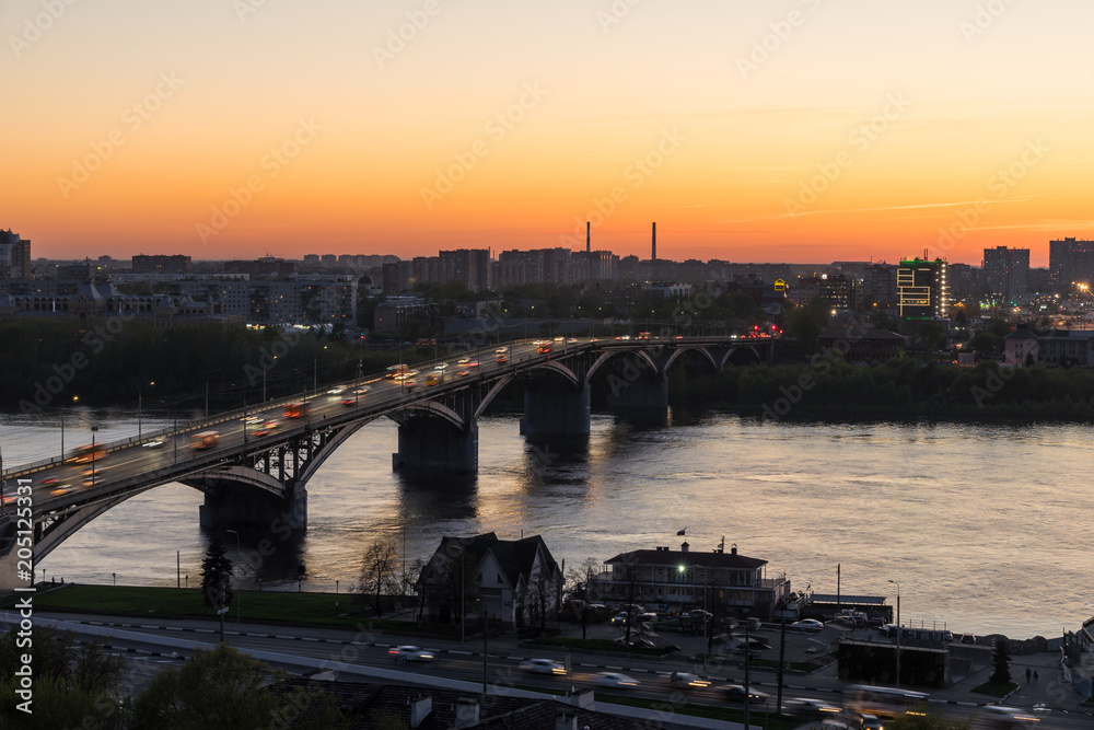 View from the high on Nizhny Novgorod city in Russia, Kanavinsky Bridge over the Oka River at sunset, moving cars on the bridge and on the road