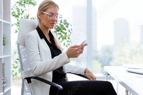 Beautiful young businesswoman using her mobile phone in the office.