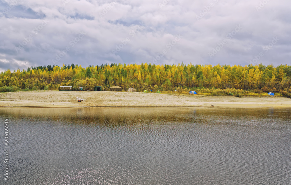 A large field camp on the autumn bank of the river