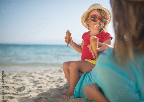Mother and doughter eating ice cream on sandy beach