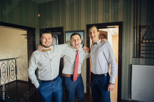 Stylish groomsmen and happy groom playing billiard in the morni