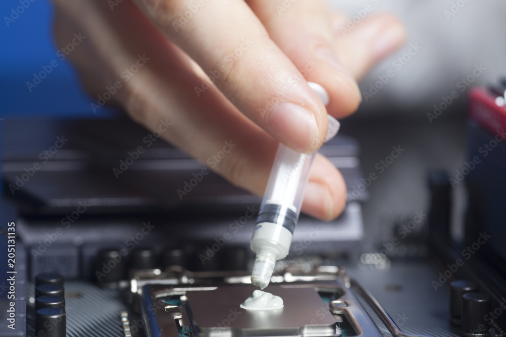 Hand with syringe applying thermal paste on the CPU processor on motherboard Hand with syringe applying thermal paste on the CPU processor on motherboard