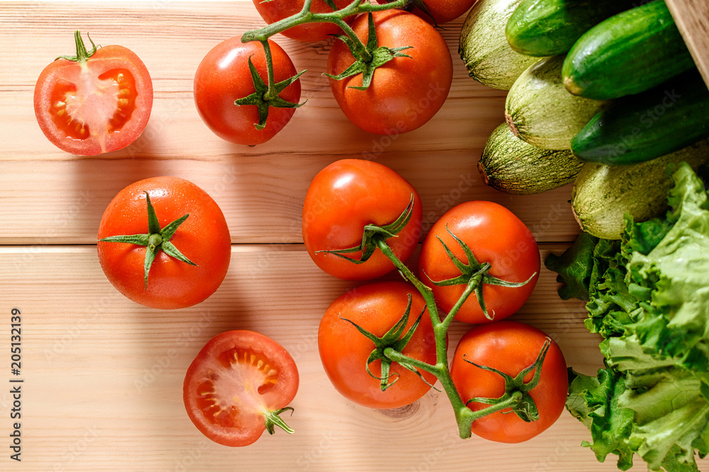 Close-up of fresh, ripe tomatoes with vegetables on wooden background. Top view. Close-up of fresh, ripe tomatoes with vegetables on wooden background. Top view.