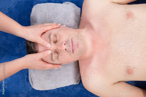 woman masseur doing head massage of temples on man in spa center