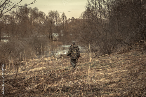 hunter man creeping forest river during hunting season