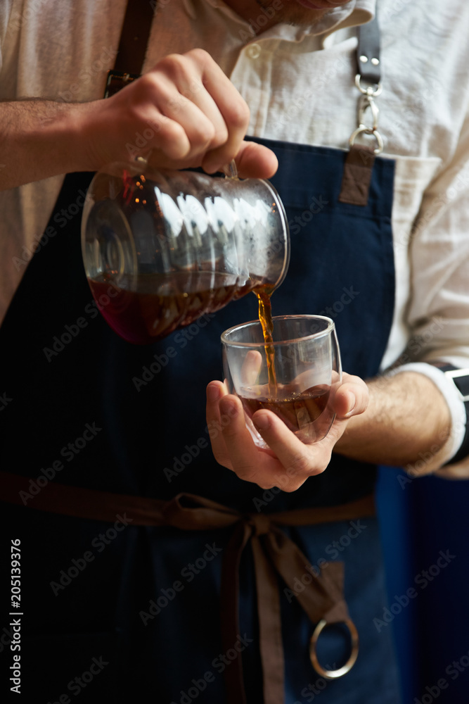 Barista pouring hot coffee into a cup, close-up