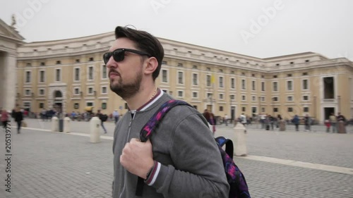 Young man from tokyo with backpack in Vatican city and St. Peter's Basilica church, Rome, Italy. Travel tourist man outdoors during holidays in Europe. Slow motion. Steadycam shot.