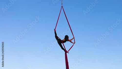 Woman performs sports gymnastic stunts on ropes.