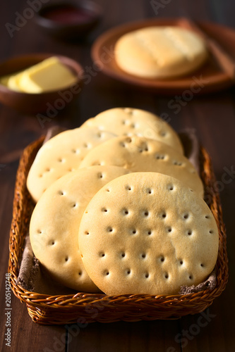 Chilenische Hallulla Brötchen in Korb, fotografiert mit natürlichem Licht (Selektiver Fokus, Fokus auf das erste Brötchen) photo