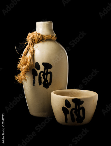 Sake bottle and cup isolated on black background