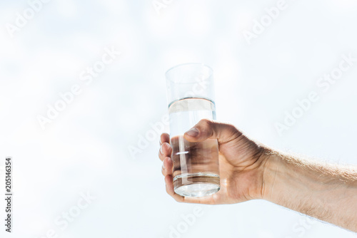 cropped shot of human hand holding glass of fresh water