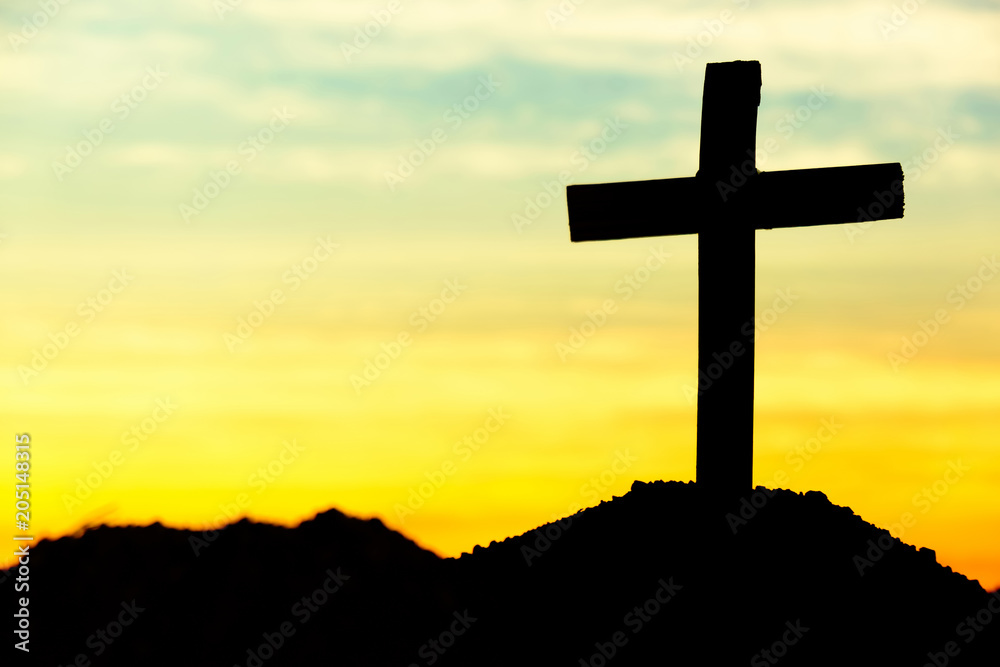 Concept conceptual cross religion symbol silhouette in nature over sunset or sunrise sky Concept conceptual cross religion symbol silhouette in nature over sunset or sunrise sky