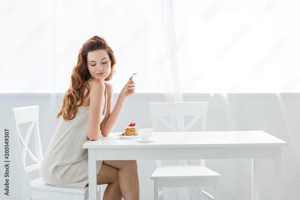 sensual young woman sitting at table with strawberry pancakes at home sensual young woman sitting at table with strawberry pancakes at home