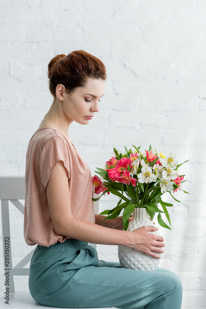 A woman sitting in a chair holding a bunch of flowers photo – Free