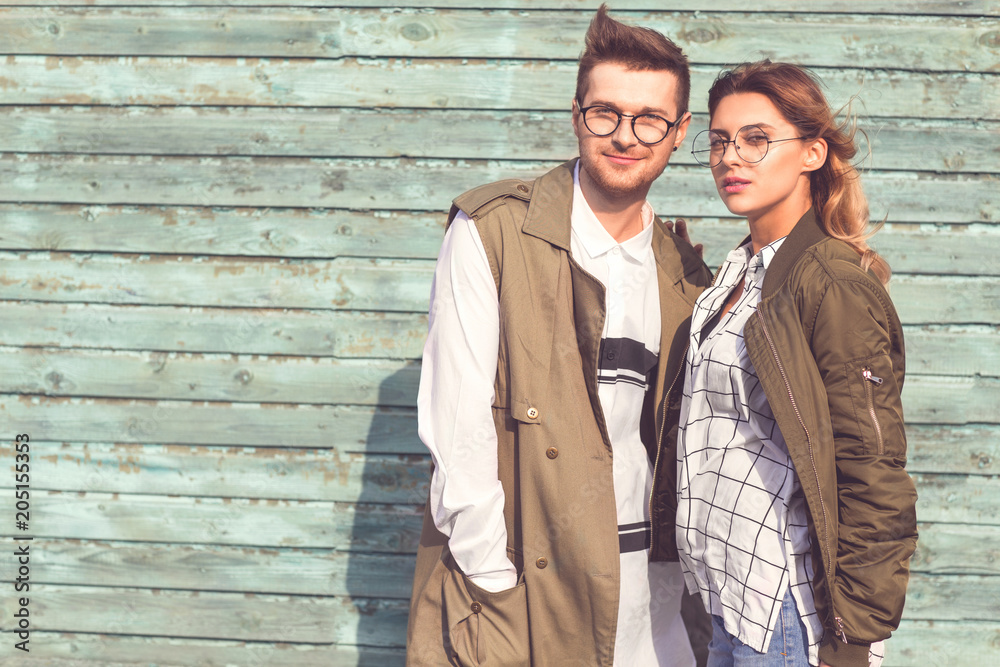 fashion couple in glasses with glasses in green clothes posing on blue wooden wall fashion couple in glasses with glasses in green clothes posing on blue wooden wall