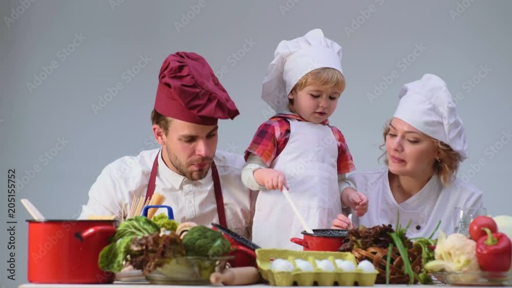Cute little boy and his beautiful parents are smiling while cooking in kitchen. Young family cooking food in kitchen. Happy family cooking together. Happy young family with Mum, Dad child cooking. Cute little boy and his beautiful parents are smiling while cooking in kitchen. Young family cooking food in kitchen. Happy family cooking together. Happy young family with Mum, Dad child cooking.
