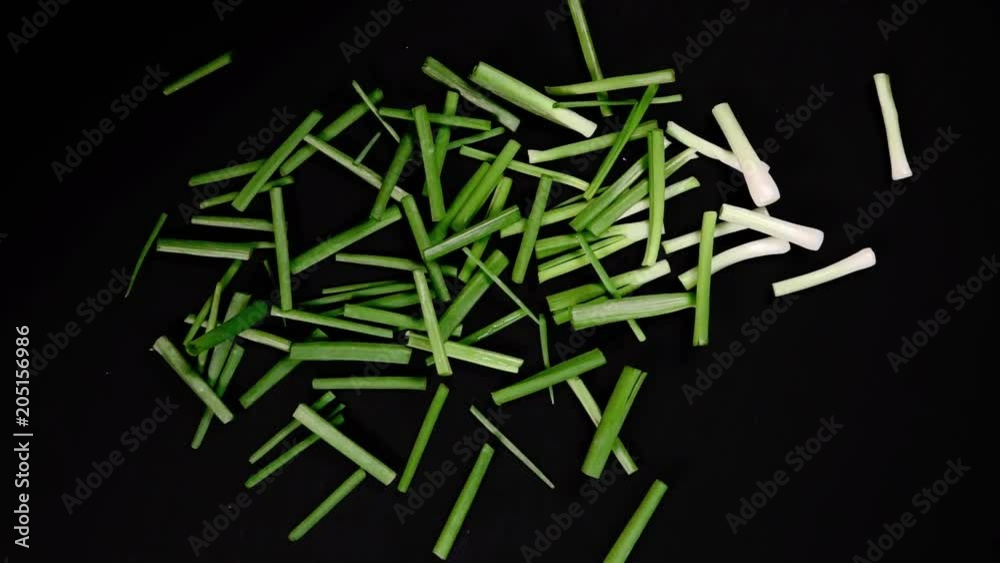 Falling fresh green onions on a black board and slices . Slow motion Falling fresh green onions on a black board and slices . Slow motion