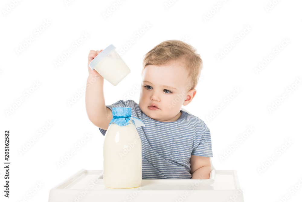 little boy with plastic container and bottle of milk and sitting in highchair isolated on white background little boy with plastic container and bottle of milk and sitting in highchair isolated on white background