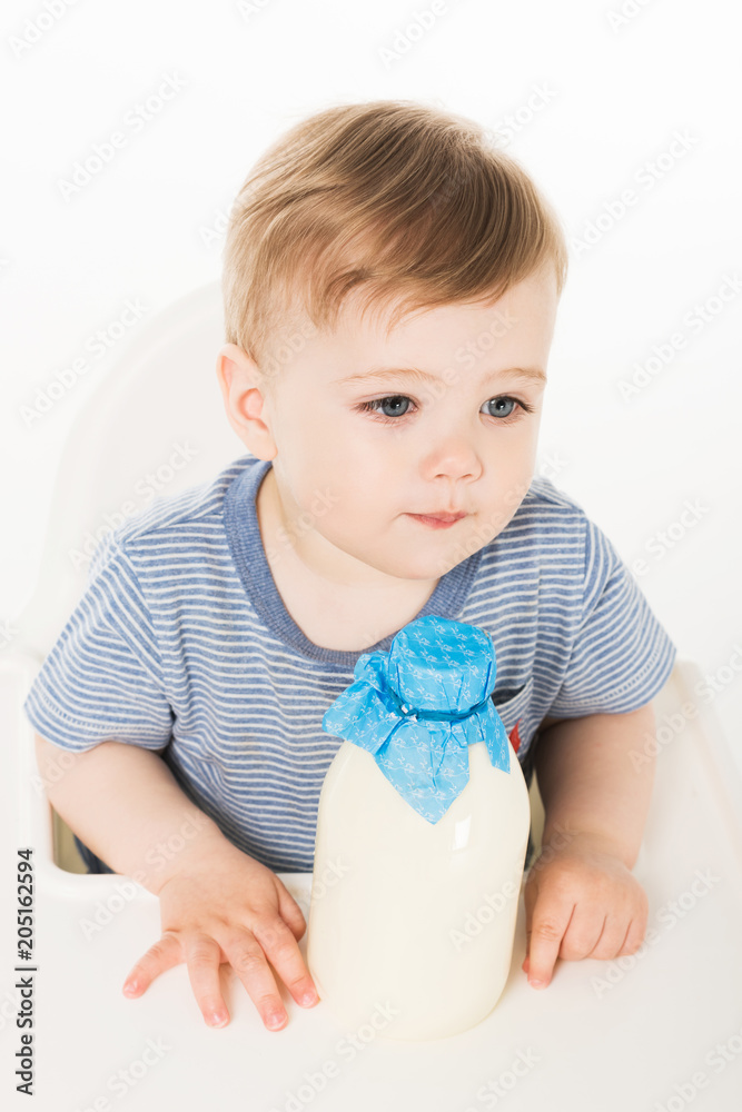 high angle view of little boy with bottle of milk and sitting in highchair isolated on white background high angle view of little boy with bottle of milk and sitting in highchair isolated on white background
