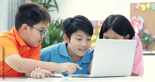 Cute Asian children using laptop together.