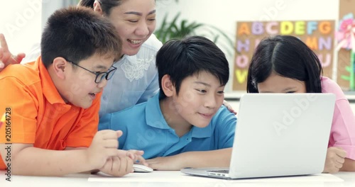 Asian woman teacher and Cute Asian children using laptop computer together.