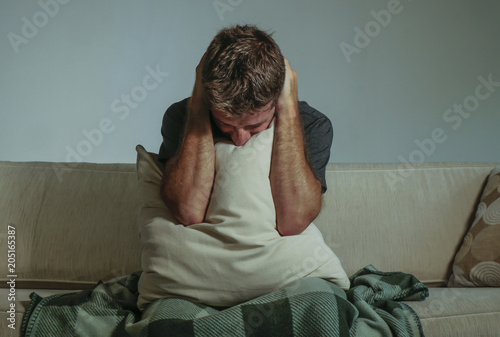 Fotografija young sad and desperate man at home sitting at sofa couch covering face with han