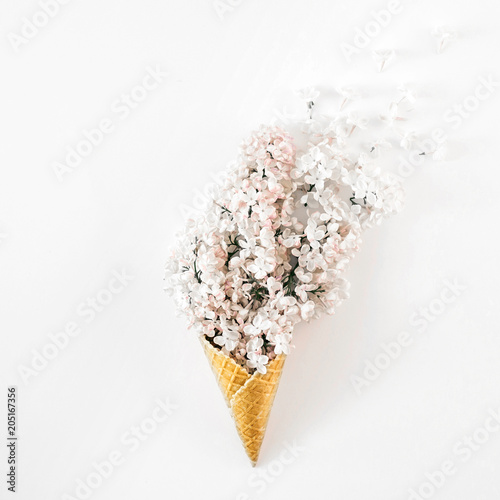 Top view ice cream cone branch white lilacs white background Minimal spring concept Flat lay