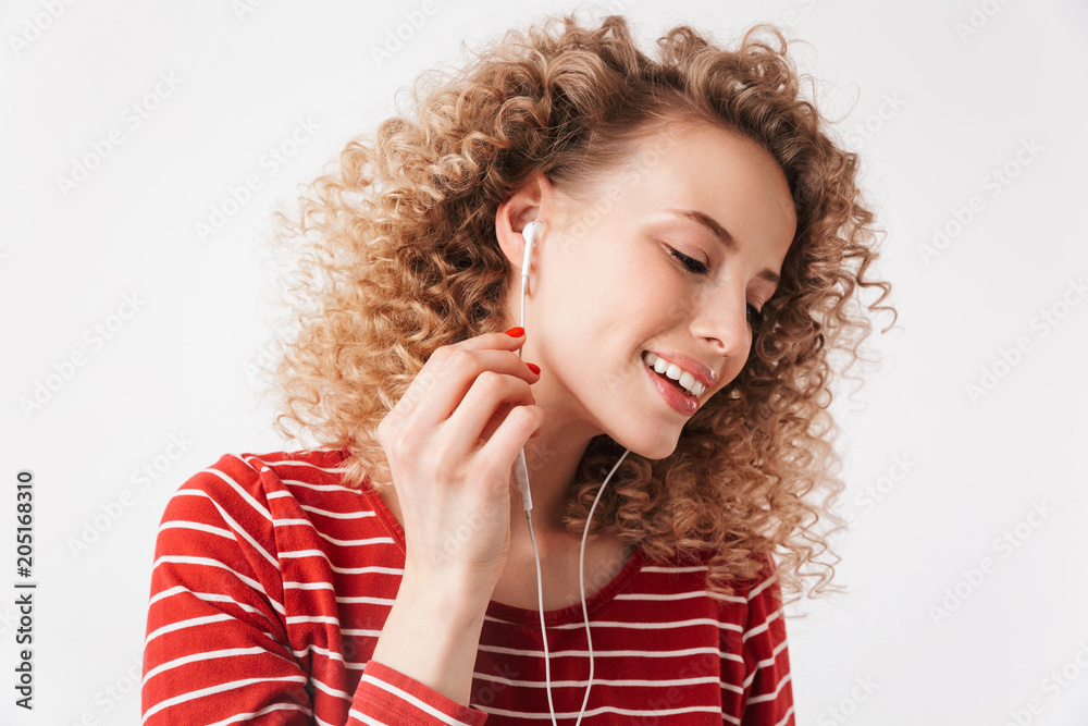 Pleased curly woman in casual clothes and earphones listening music Pleased curly woman in casual clothes and earphones listening music