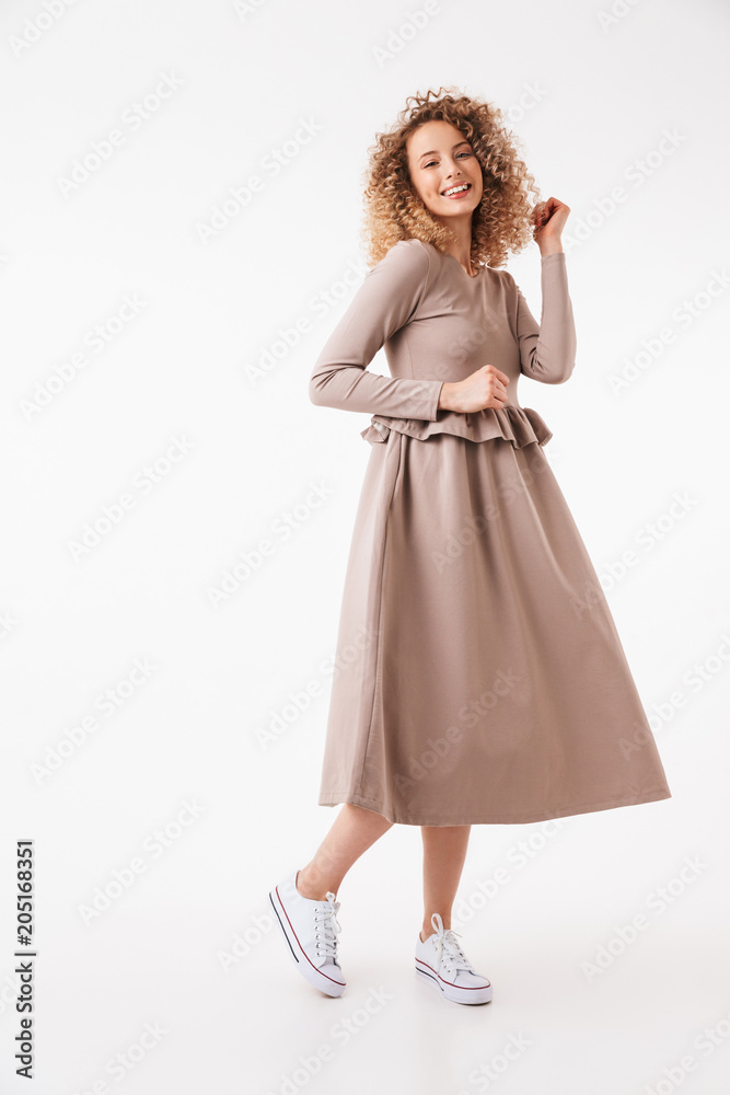 Full length image of Cheerful blonde curly woman in dress