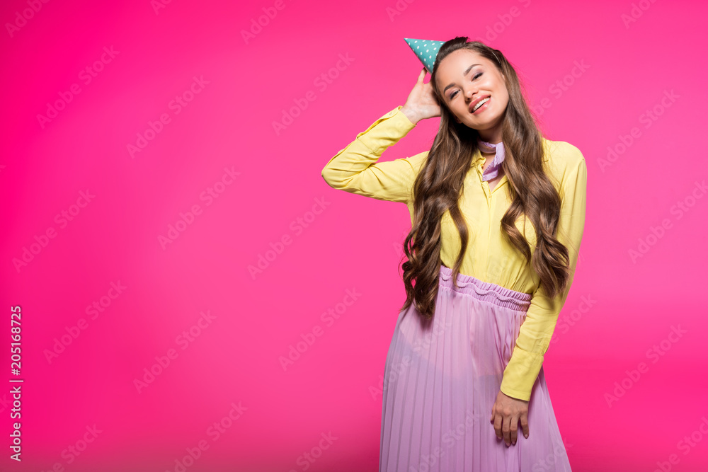 smiling attractive woman with party hat isolated on pink