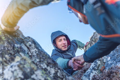 Man helps his friend to climb to the top. Hiker gives a hand to pull up the on mountain. photo