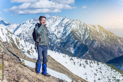 Young man with phone in hand on the top of a snowy mountain. Concept availability of mobile connection