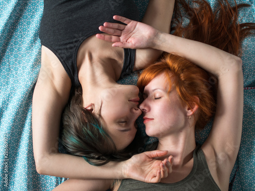 Two girlfriends lay on the bed, top view