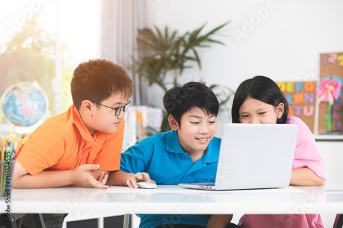 Cute Asian children using laptop together.