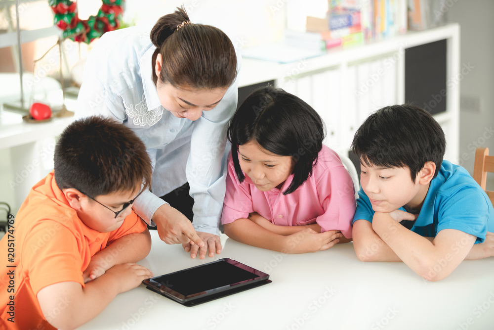 Asian teacher and kids entertaining themselves using digital tablet Asian teacher and kids entertaining themselves using digital tablet