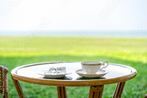 Set spoon fork and coffee cup on table in restaurant with nature background, selective focus. 