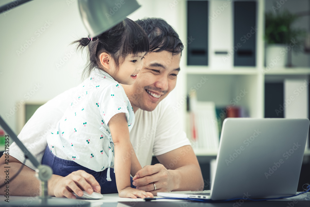 Asian family and little girl ,while dad works with notebook on work table. Asian family and little girl ,while dad works with notebook on work table.