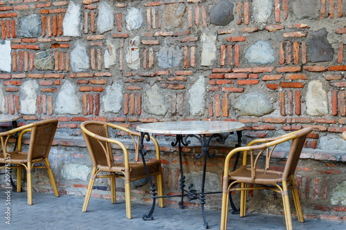 Tables and chairs in outdoor cafe. Patio set against stone wall