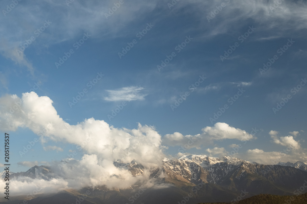Fototapeta premium the tops of the mountain ranges snow-covered in the clouds of the Karachay-Cherkess Republic, the Caucasus, in the spring evening