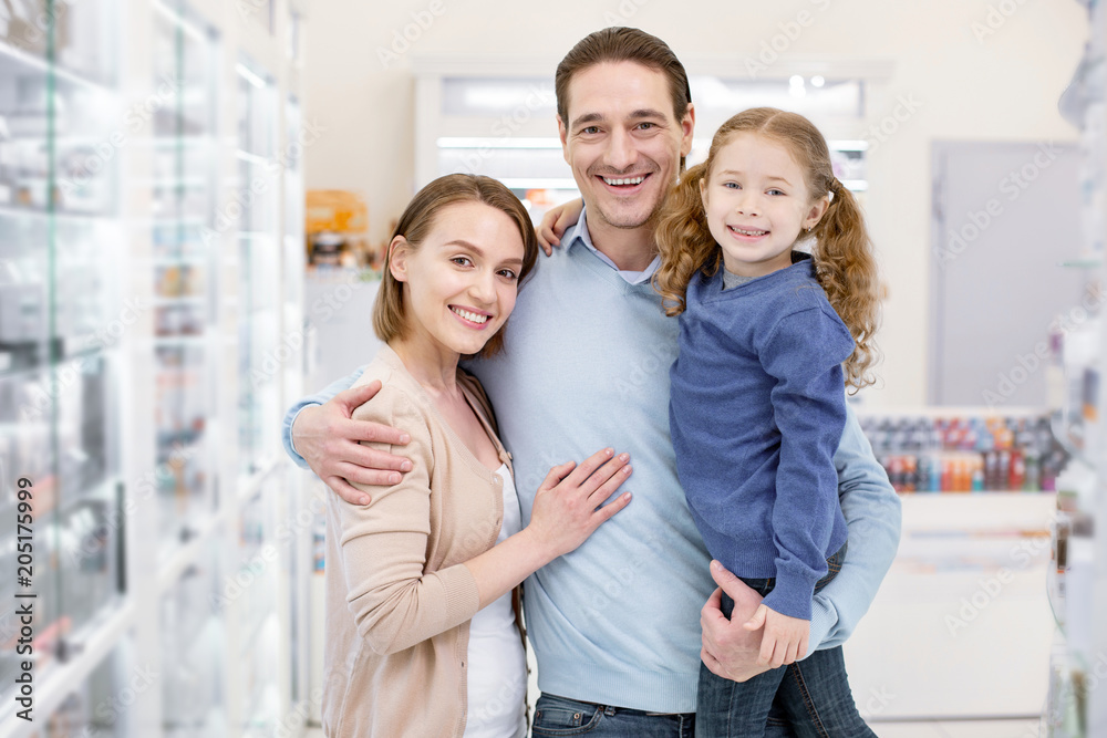 Family shopping. Enthusiastic jovial family hugging and looking at camera