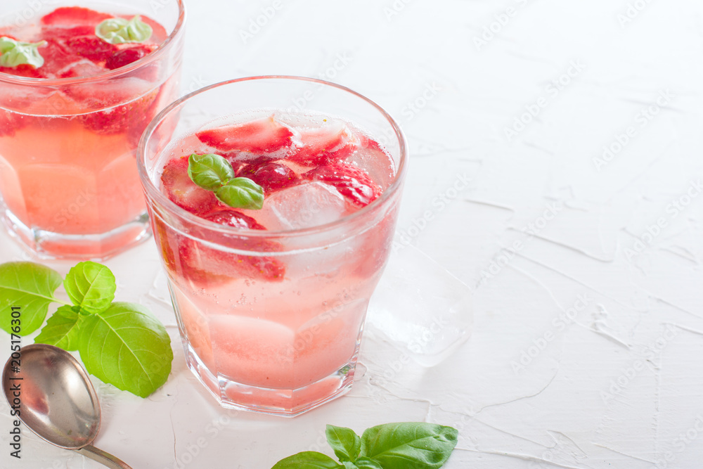 Fresh cool summer drink with strawberries and green basil in glass glasses on white table, horizontal, copy space Fresh cool summer drink with strawberries and green basil in glass glasses on white table, horizontal, copy space