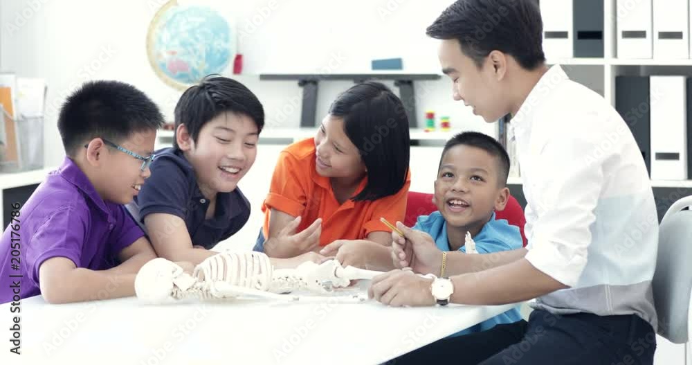 Asian teacher expanding to student in anatomy class with skeleton dummy . Asian teacher expanding to student in anatomy class with skeleton dummy .