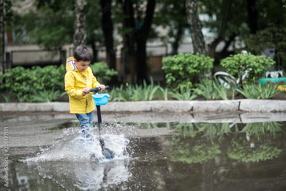 A wet child is jumping in a puddle. Fun on the street. Tempering in summer A wet child is jumping in a puddle. Fun on the street. Tempering in summer
