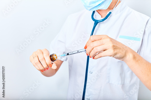 Woman doctor filling medicine from ampule into syringe.