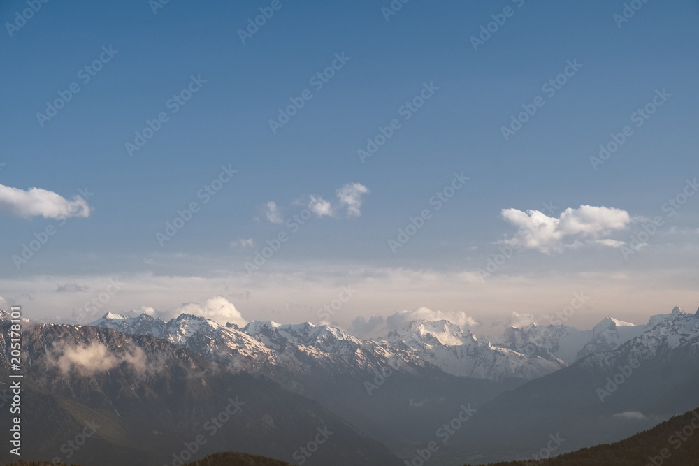 the tops of the mountain ranges snow-covered in the clouds of the Karachay-Cherkess Republic, the Caucasus, in the spring evening the tops of the mountain ranges snow-covered in the clouds of the Karachay-Cherkess Republic, the Caucasus, in the spring evening