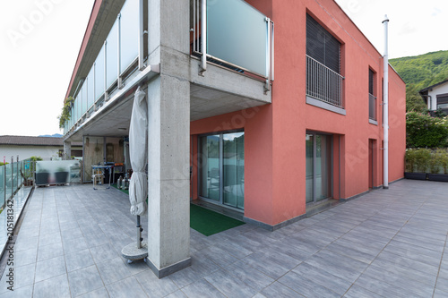 Red building exterior with large terrace and glass parapet