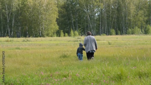 Grandmother and little granson walking in the countryside holding hands. Family leisure outdoor photo