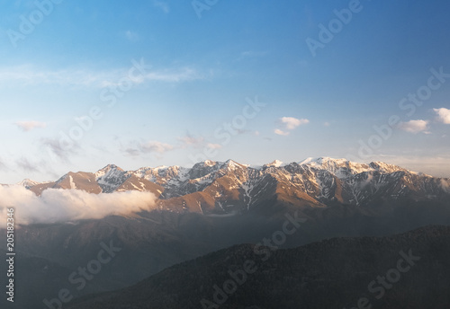 the tops of the mountain ranges snow-covered in the clouds of the Karachay-Cherkess Republic, the Caucasus, in the spring evening