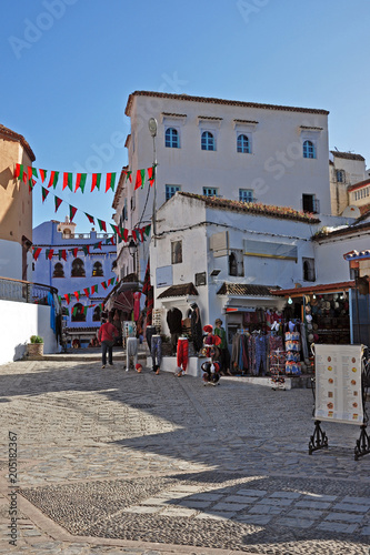 Street in ancient Chefchaouen with a shop and colored flags. Morocco.
