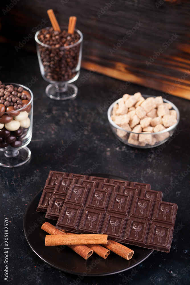 Chocolate tablet next to other candies on dark wooden background Chocolate tablet next to other candies on dark wooden background
